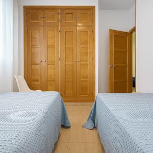 een slaapkamer met 2 bedden en een houten kast bij Apartamento Ría Punta Umbría in Punta Umbría