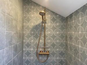 a shower in a bathroom with a wall at Le Corps de Garde du château in Saint-Martin-des-Champs