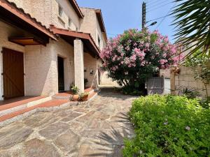 a house with a stone walkway and a tree with pink flowers at L'Escapade du Midi in La Celle-sous-Gouzon