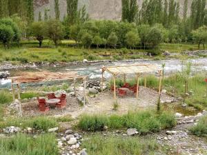 a picnic area with tables and chairs next to a river at Hotelgreenland in Skardu