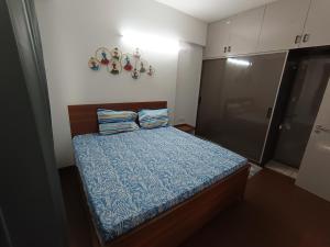 a small bedroom with a bed with a blue comforter at Fully Furnished Flat WTC 106 in Gurgaon +29 photos