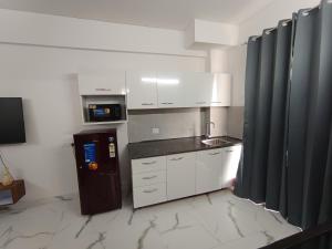 a kitchen with white cabinets and a black refrigerator at Fully Furnished Flat WTC 106 in Gurgaon