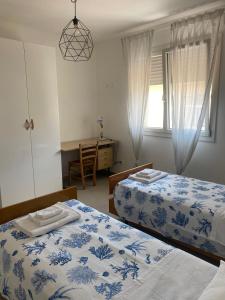a bedroom with two beds and a desk and a window at MAISON ANZIO E ROSA in Ravenna