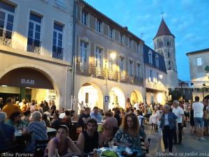a crowd of people sitting at tables in a street at Maison Familiale Gers 12 pers in Fleurance