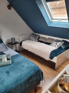 a attic bedroom with two beds and a window at Les Hirondelles à 5 mn de l' aeroport in Beauvais