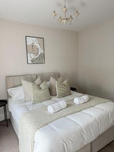 ein großes weißes Bett mit Kissen und einem Kronleuchter in der Unterkunft Rickmansworth Lodge in Rickmansworth