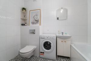 a white bathroom with a washing machine and a sink at Cozy Attic in Marki