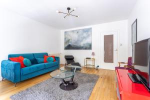 a living room with a blue couch and a glass table at Jean Jaures - Appart Moderne avec Balcon & Parking in Chamalières +5 photos