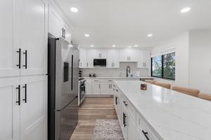 a kitchen with white cabinets and a black refrigerator at All-New Luxe Stay Views, Sauna & Hot Tub villa in Holladay