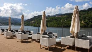 un grupo de sillas y sombrillas en un patio en Douro Royal Valley Hotel & Spa, en Riba Douro