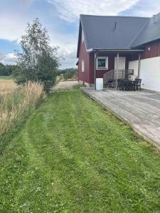 a red barn with a deck and a grass field at Rural living near Båstad, Mellbystrand in Edenberga