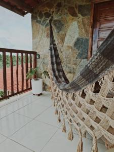 un hamac sur un porche avec un mur de pierre dans l'établissement Wind Village Icaraizinho, à Icaraí 1 autre photo