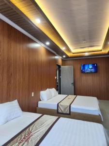 a bedroom with two beds and a tv on the wall at New Life Homestay in Phan Thiet