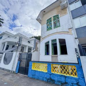 a white house with a blue and yellow fence at Caminito Salvador Hostel in Salvador