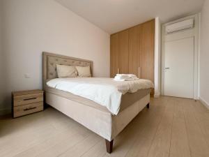 a bedroom with a large bed and a wooden cabinet at Magnolia Apartment Luxury and Relaxation on the Sava in Belgrade