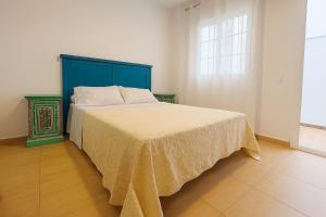 een slaapkamer met een bed met een blauw hoofdeinde en een raam bij Apartamento Ría Punta Umbría in Punta Umbría