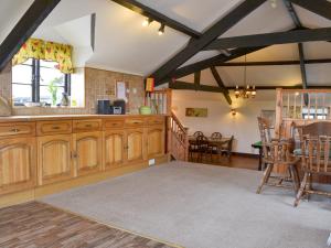 a kitchen with wooden cabinets and a dining room at The Old Granary in Kilkhampton +22 photos