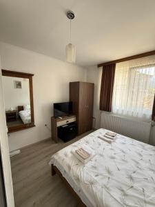a bedroom with a white bed and a television at Къща Цвети in Dobrinishte