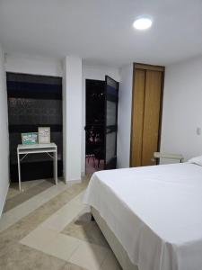 a bedroom with a white bed and a table at EstadioMedellin in Medellín