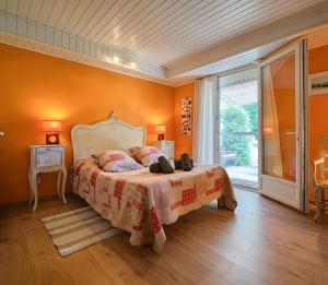 a bedroom with a bed with an orange wall at Gite La Bastide De La Coda in Châteauneuf-du-Rhône