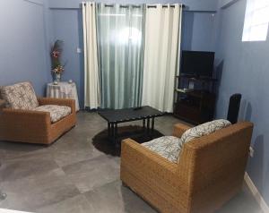 a living room with two chairs and a television at LHM Apartments in Christ Church