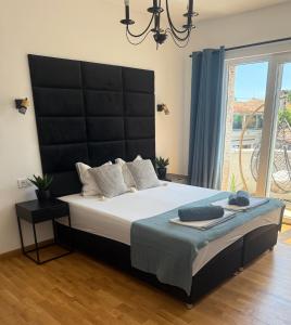 a bedroom with a large bed with a black headboard at Holiday Apartment ORA in Balchik