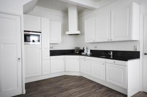 a white kitchen with white cabinets and black counter tops at Brink 3 Diever in Diever