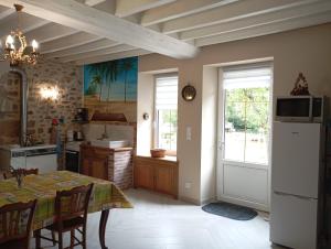 a kitchen with a table and a kitchen with a refrigerator at La garçonnière in Gesvres