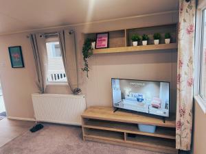 a living room with a flat screen tv on a shelf at Sandy Nights in Tywardreath