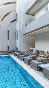 a swimming pool in a building with couches and a swimming pool at Zorbas Lifestyle Hotel in Georgioupolis