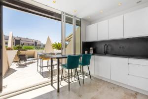 a kitchen with white cabinets and a table with green chairs at AmbassadOr Elegance and comfort steps from the naturist beach in Cap d'Agde
