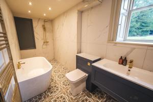 a bathroom with a tub and a toilet and a sink at The Victorian Suite in Marske