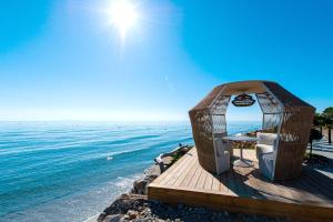a gazebo on the beach next to the water at Hôtel Pineto in Biguglia