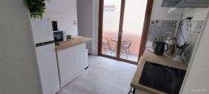 MirecourtにあるAppartement Mirecourt Centreの白いキャビネット付きのキッチン、バルコニーが備わります。 +3枚の写真