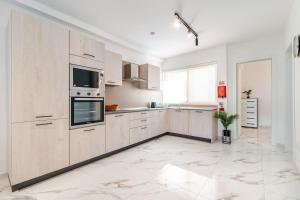 a large kitchen with white cabinets and appliances at Modern 2BR Escape in St Julians in St Julian's
