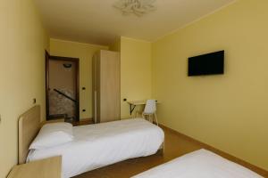 two beds in a room with a tv on the wall at Guest House Le Risaie in Asigliano Vercellese