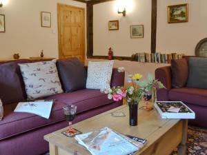 a living room with a purple couch and a table at Henley Bridge Holiday Cottage in Ashburnham