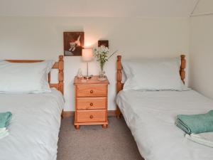 a bedroom with two beds and a nightstand with a vase of flowers at Henley Bridge Holiday Cottage in Ashburnham +5 photos