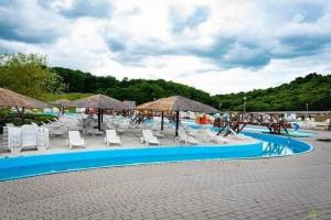 a swimming pool with chairs and umbrellas and a pool at Cole si Denisa in Beclean