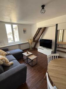 a living room with a couch and a tv and a table at Le Nid Dolois in Dole