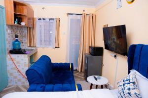 a living room with a blue couch and a tv at Marie's Studios Naivasha in Naivasha