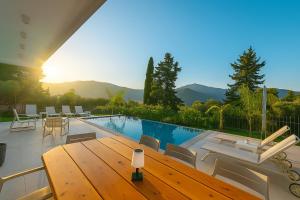 a villa with a pool and a wooden table at Villa Harmony Luxury Resort in Corfu Town