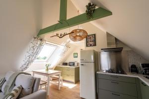 a kitchen with a refrigerator and a table in a room at Les Gîtes Shu-no in Pléhédel