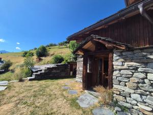 a stone building with a door in a field at Charmant Appartement 4 personnes - Montvalezan in Montvalezan