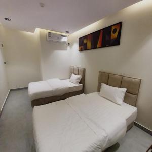a room with two beds and a painting on the wall at منتجع هدب للشقق المخدومة in Taif