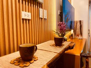 two cups on a wooden table with flowers on it at Cool Suites at SMDC Wind Residence Tagaytay in Tagaytay