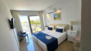a bedroom with a bed with blue sheets and a window at NissiLant hotel & suites in Ayia Napa +69 photos