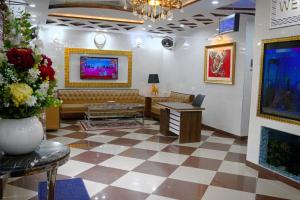 a waiting room with a couch and a tv at Neshaz Hotel & Suites in Lahore
