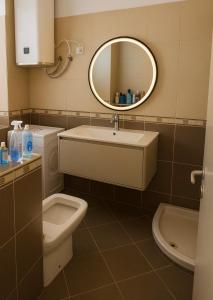 a bathroom with a sink and a toilet and a mirror at Entire Apartment near Air Albania in Tirane