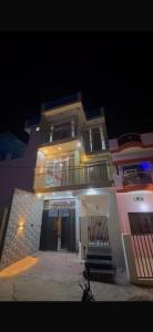 a large white building with a black door at night at Rishi home stay in Bhauli